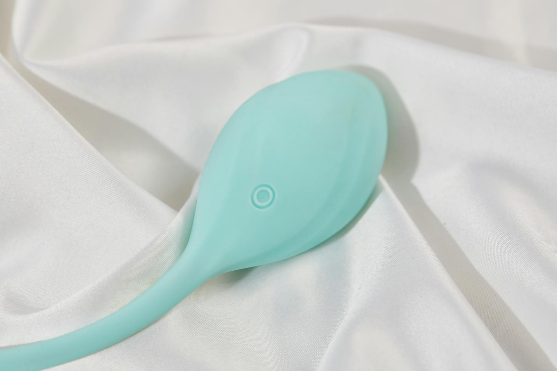 A sleek teal lemon vibrator resting on soft white fabric