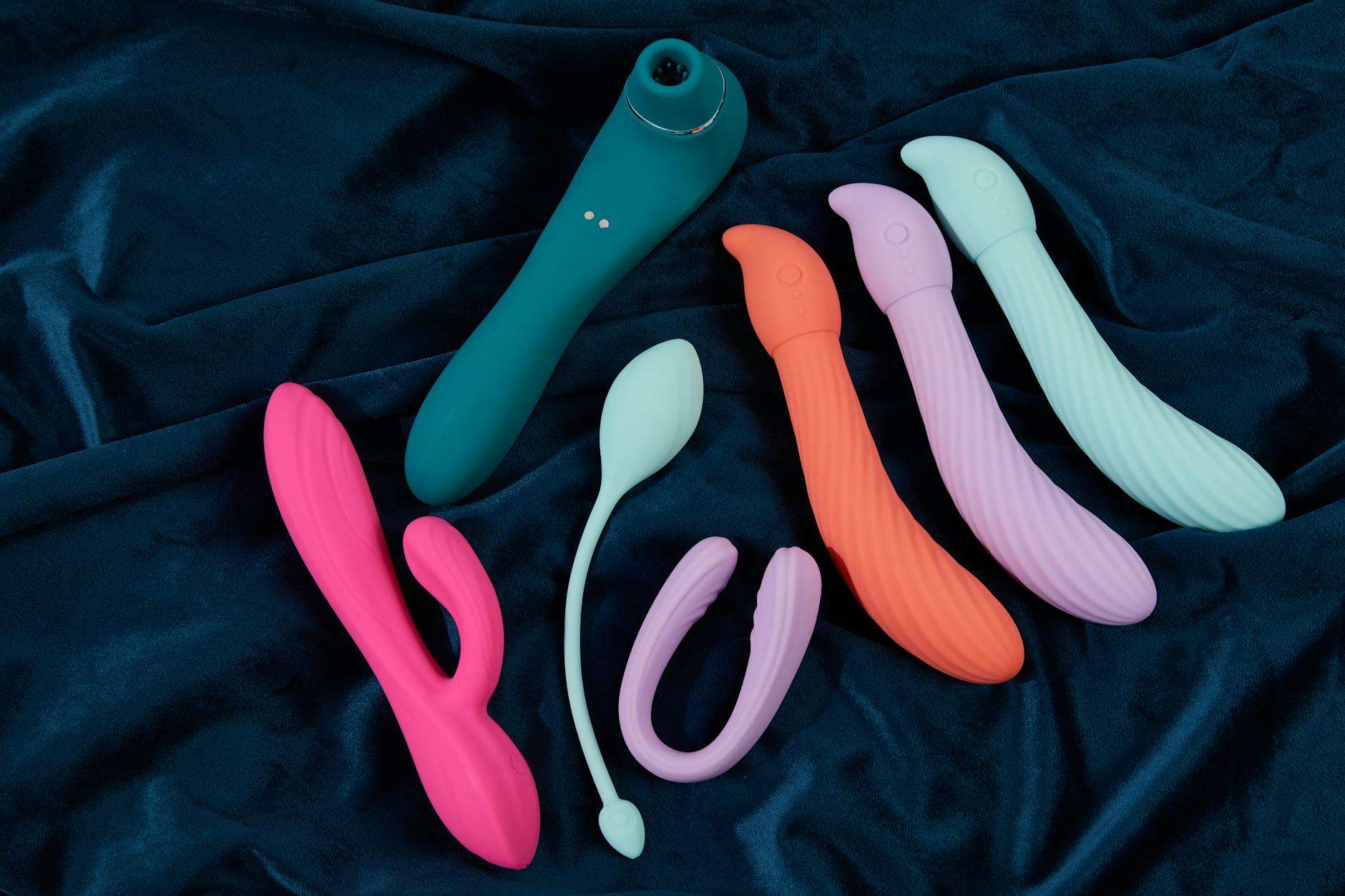 A teal lemon clitoral vibrator on smooth white silk fabric