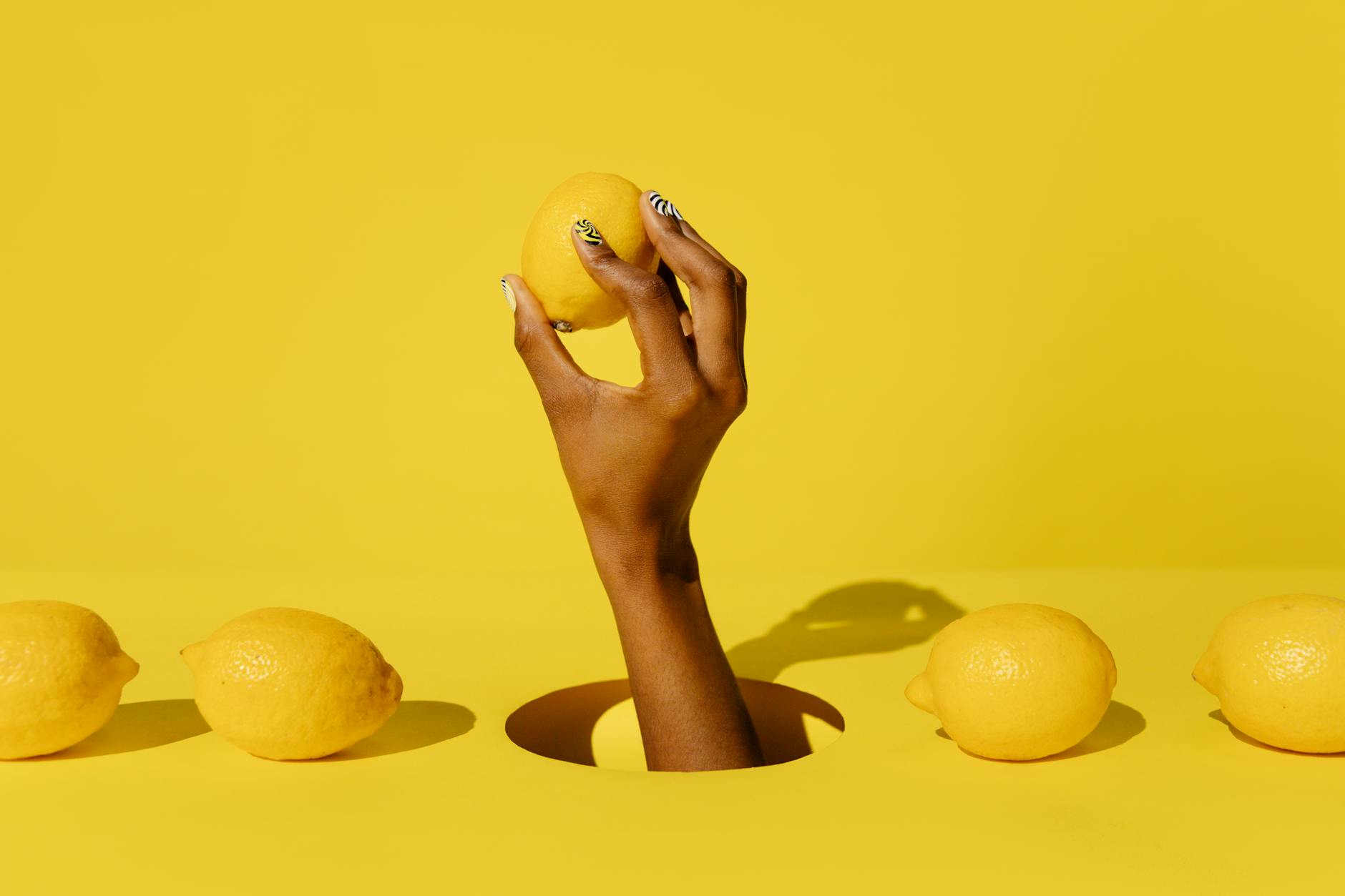 A hand holding a fresh lemon against a bright yellow background, symbolizing reclaiming your right to pleasure.