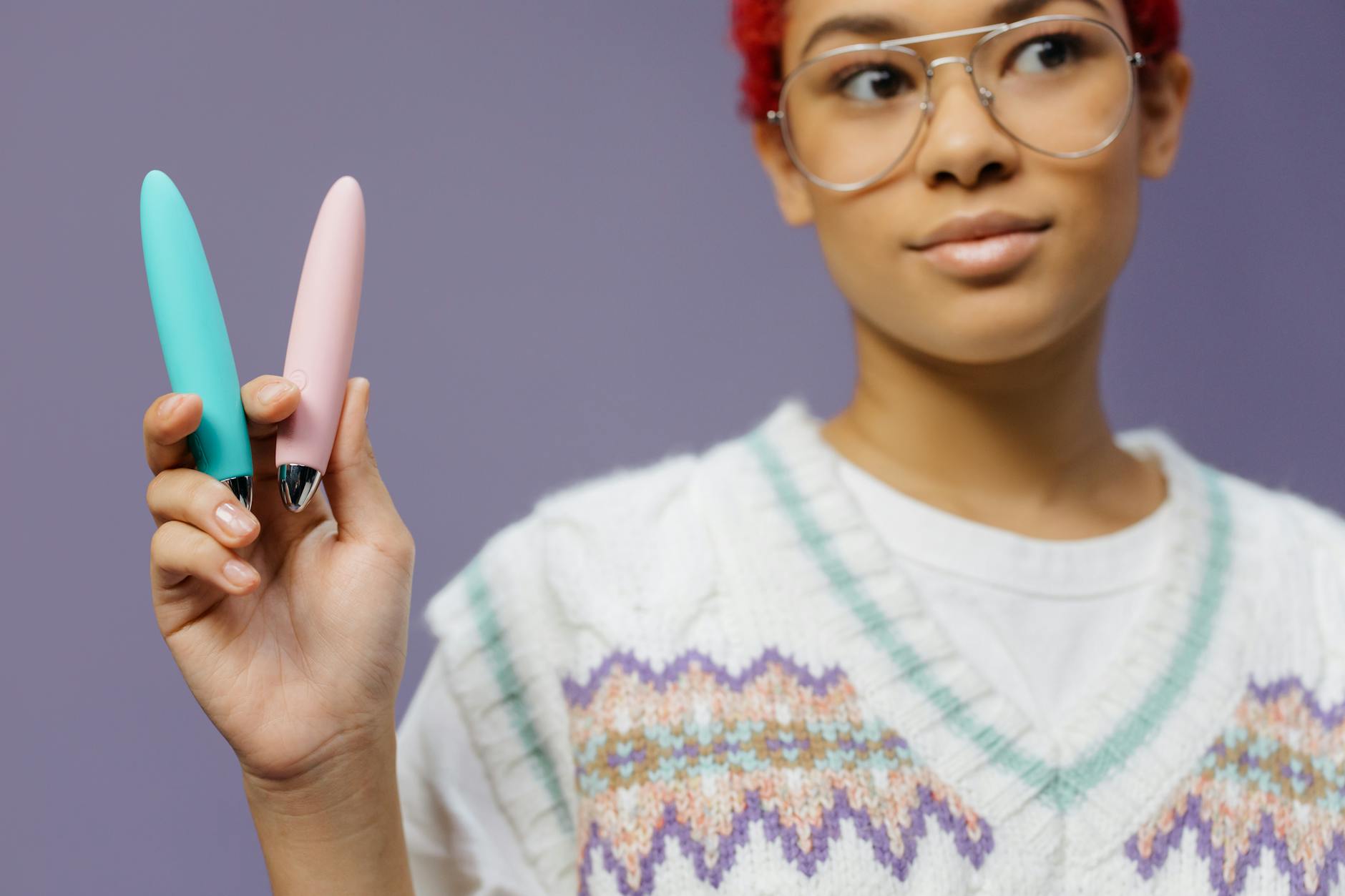 A person holding colorful vibrators including lemon clitoral vibrators against a purple background