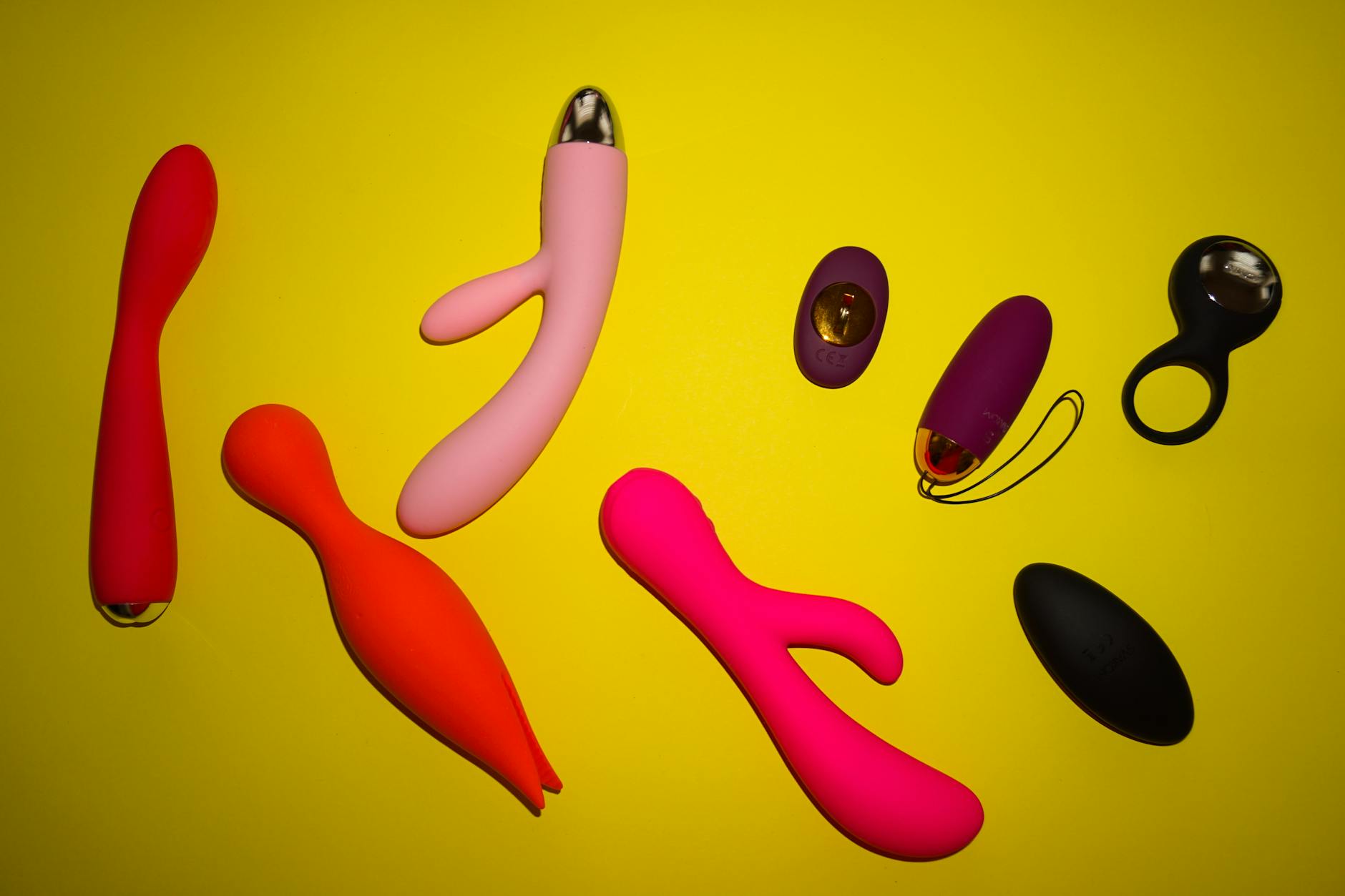 Hands holding pink and blue vibrators against a soft pastel background