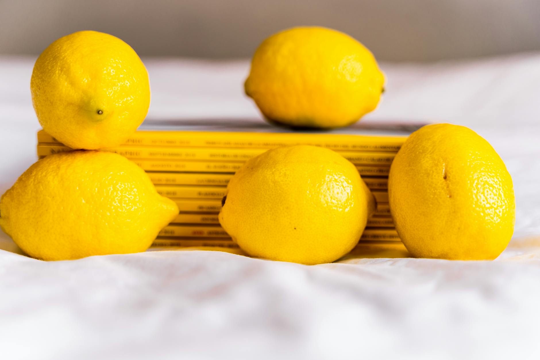 Fresh yellow lemons arranged on white tablecloth with stacked books, symbolizing post-recovery sensory restoration